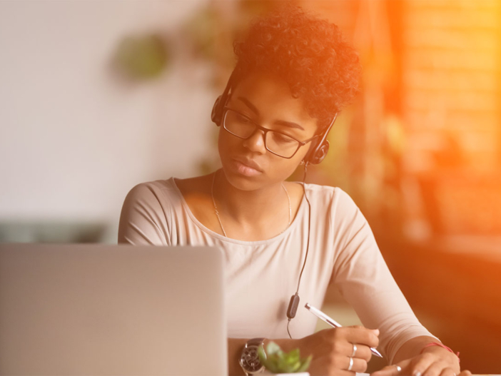 Woman working at laptop with headphones